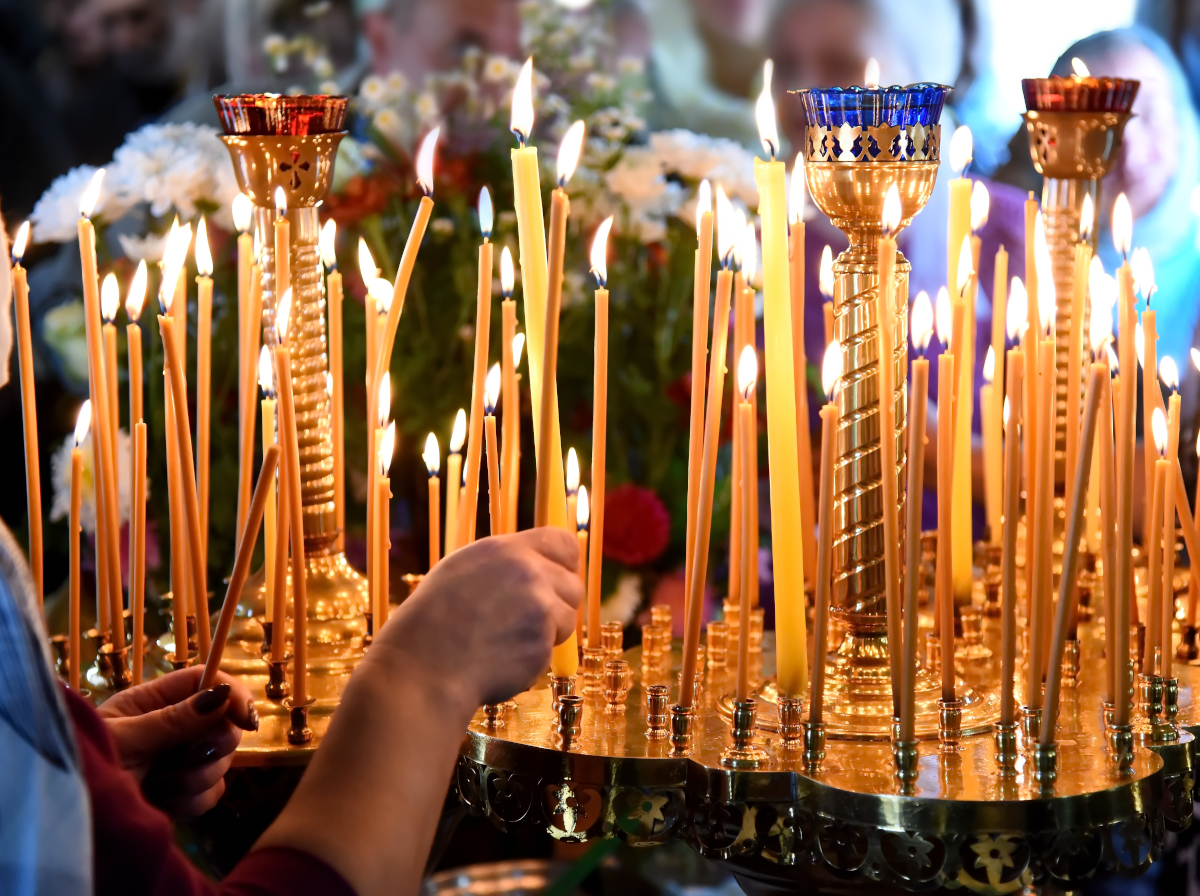 Ranks of lit beeswax candles in a church