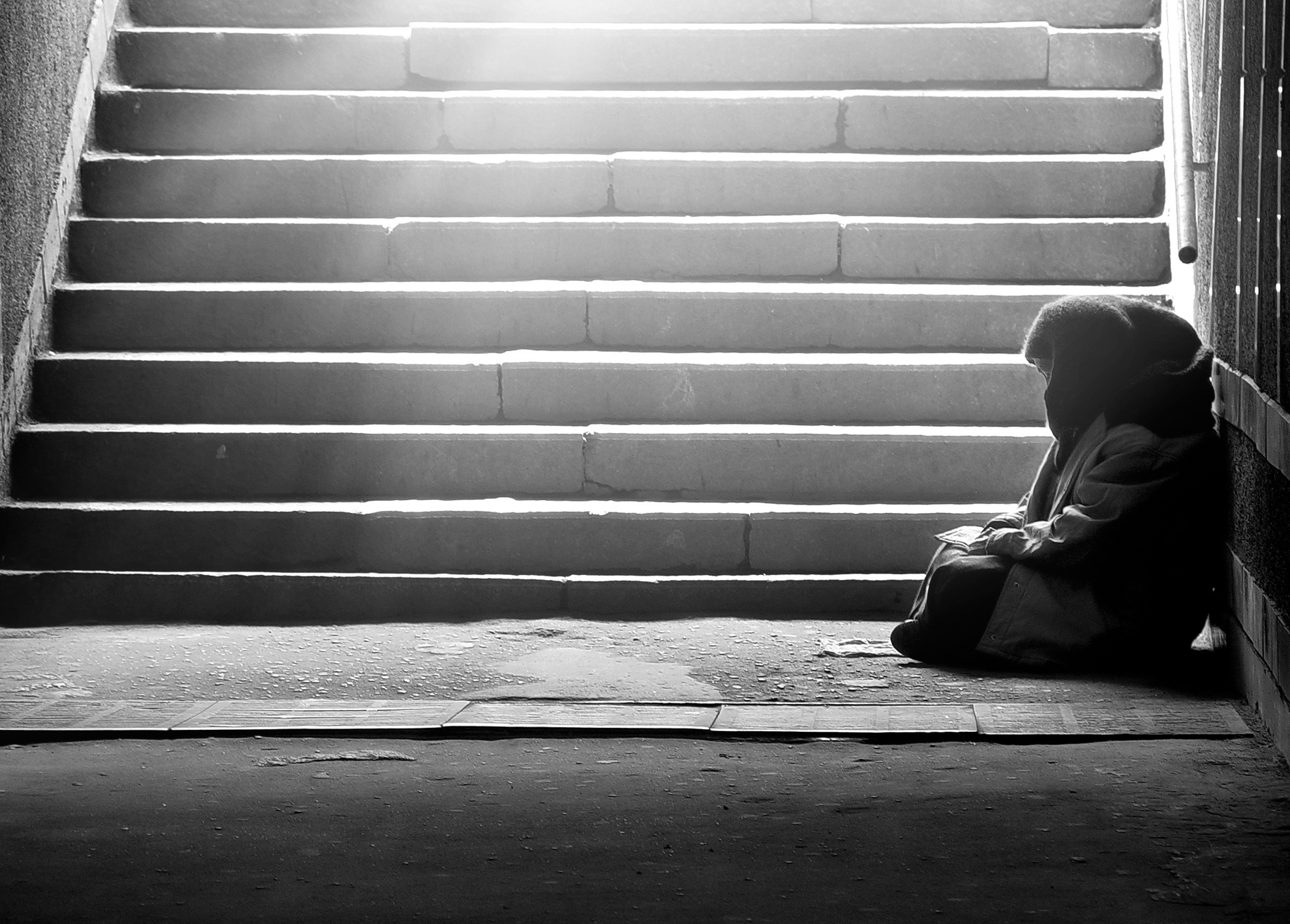 Homeless woman reading the book in subway under the sunlight 