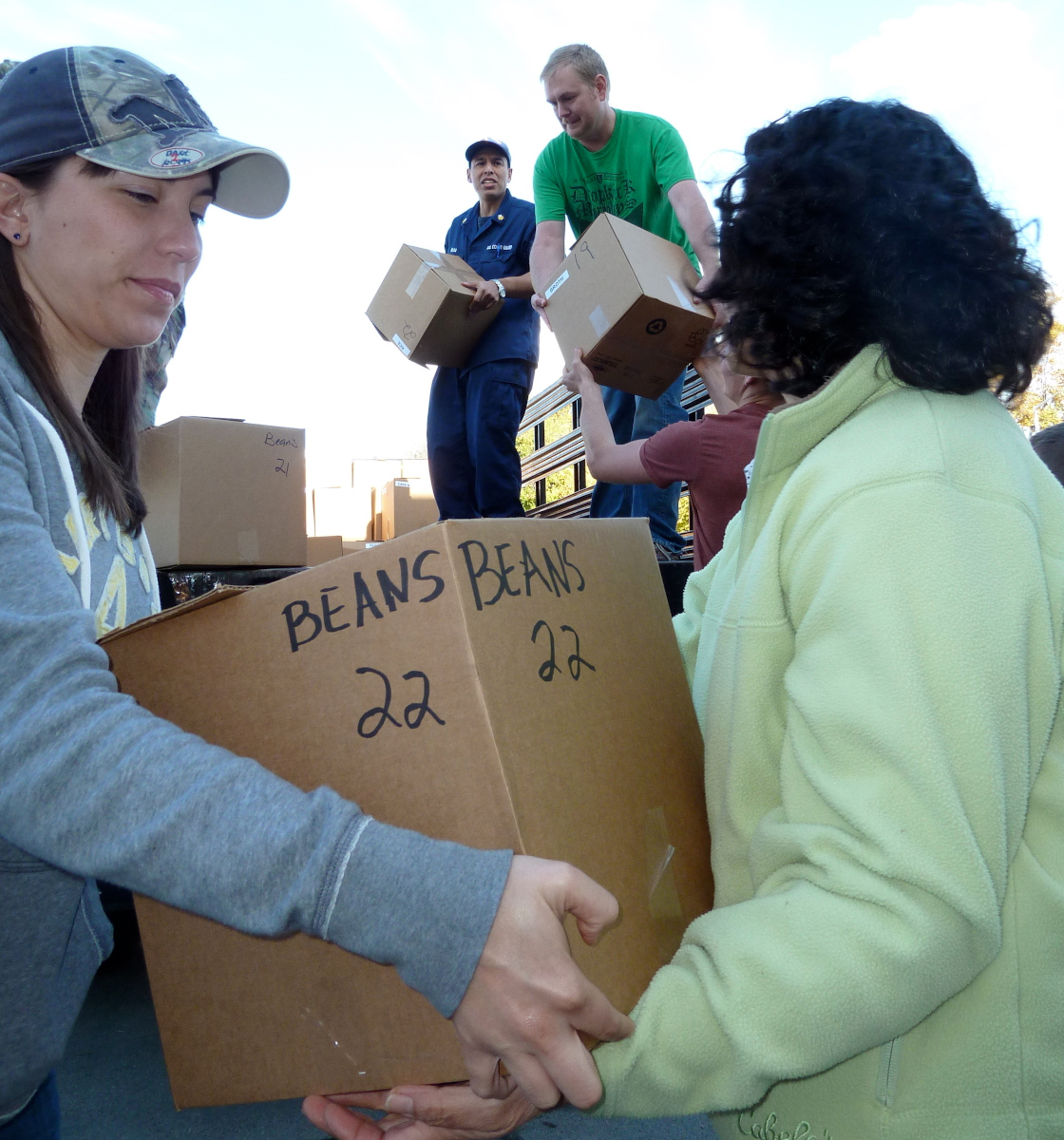 Food bank volunteers carrying boxes of canned beans