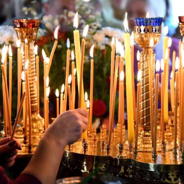Ranks of lit beeswax candles in a church