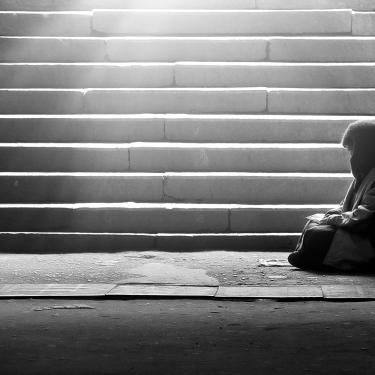 Homeless woman reading the book in subway under the sunlight 