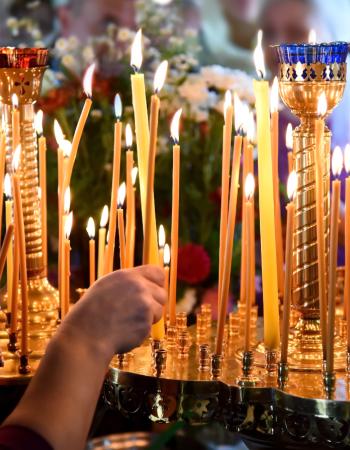 Ranks of lit beeswax candles in a church