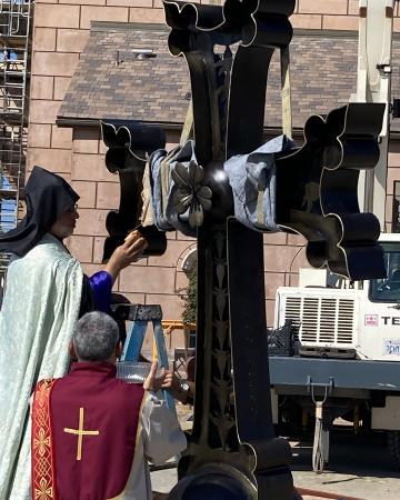 Photo of a priest blessing the cross for the top of the church.