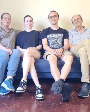 Patricia Bouteneff sits on a couch with her husband and two children