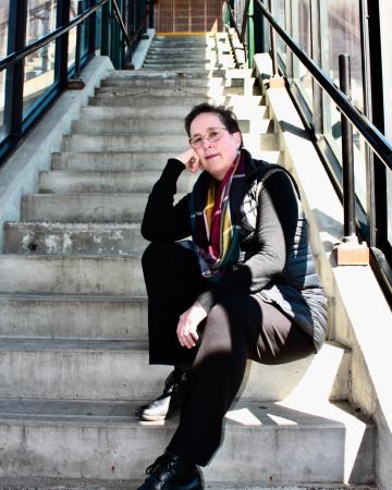 Patricia Bouteneff sits on a set of stairs and looks at the reader.