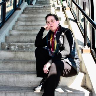 Patricia Bouteneff sits on a set of stairs and looks at the reader.